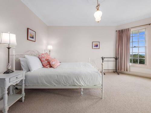 a bedroom with a white bed and a window at The Folly in Bilpin