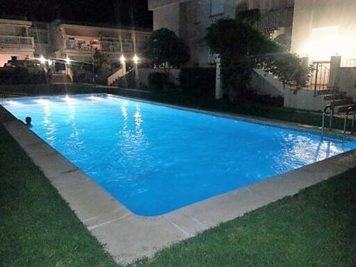 una gran piscina azul en un edificio por la noche en Apartamento en Vinaros, en Vinarós