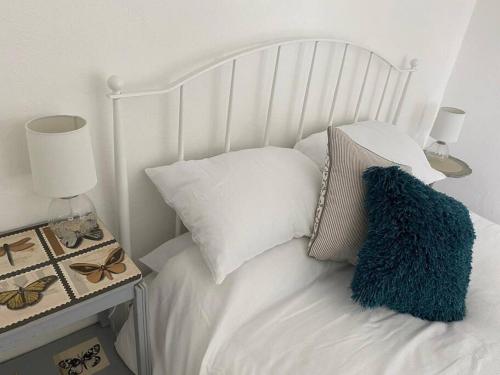 uma cama branca com almofadas brancas e uma almofada azul em Delightful Artistic Granite Barn in Rural Hamlet em Launceston