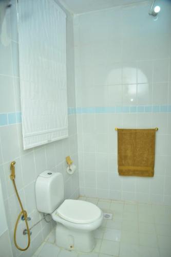 a white bathroom with a toilet and a towel at La Neisha Hotel Zanzibar in Stone Town