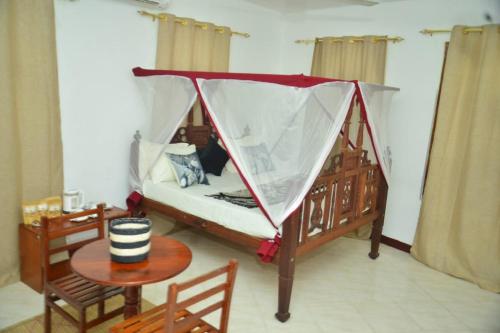 a bed with a canopy in a room with a table at La Neisha Hotel Zanzibar in Stone Town