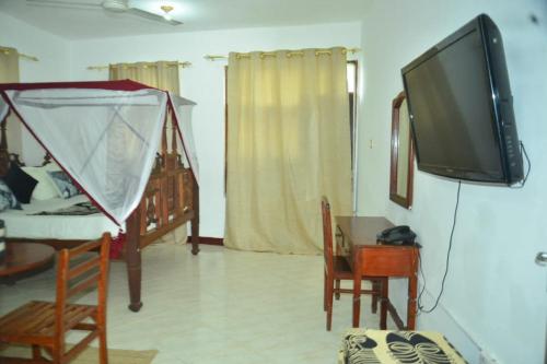 a living room with a tv and a table with chairs at La Neisha Hotel Zanzibar in Stone Town