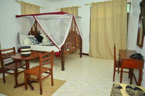 a room with a bed and a table and chairs at La Neisha Hotel Zanzibar in Stone Town
