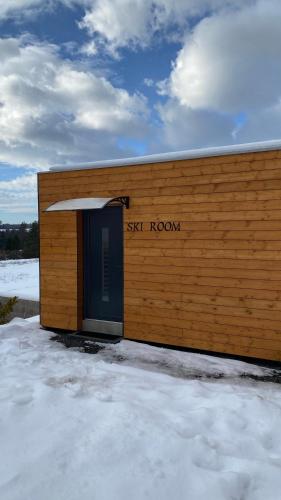 a wooden building with a blue door in the snow at Chalet Sijkovsky in Stará Lesná