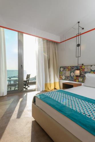 a bedroom with a bed and a view of the ocean at Folie Marine Hotel & Beach Club in Jal
