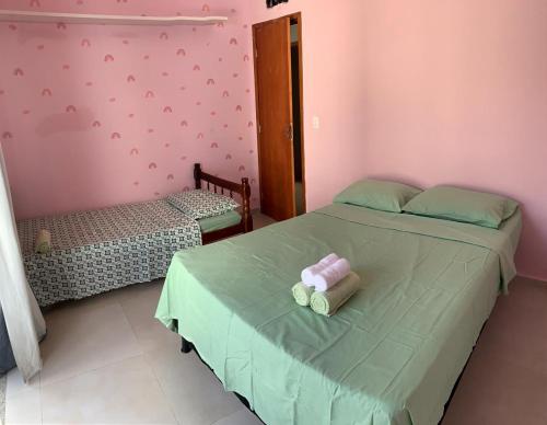 a bedroom with two beds with green sheets and pink walls at RB hospedagem in Cabo Frio