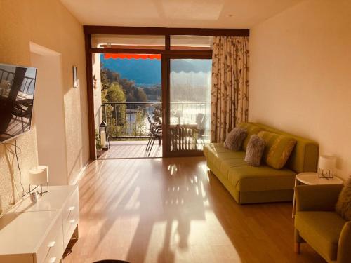 a living room with a couch and a balcony at Appartement direkt am Ossiachersee in Villach