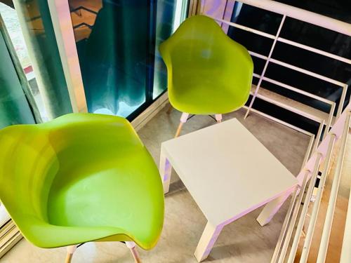 2 sillas verdes y una mesa blanca en el balcón en Room For 2 Person Close to Metro en Dubái