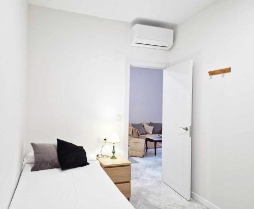 a white bedroom with a bed and a living room at Alojamientos Fenix in Murcia