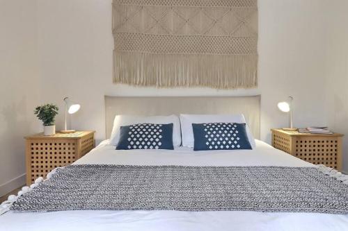 ein Schlafzimmer mit einem weißen Bett mit blauen Kissen in der Unterkunft Le Bosco - Parking et calme in Valence
