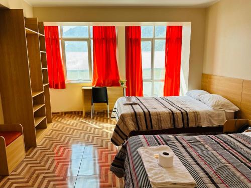 a hotel room with two beds and red curtains at LA CASONA DE YANAHUANCA in Yanahuanca