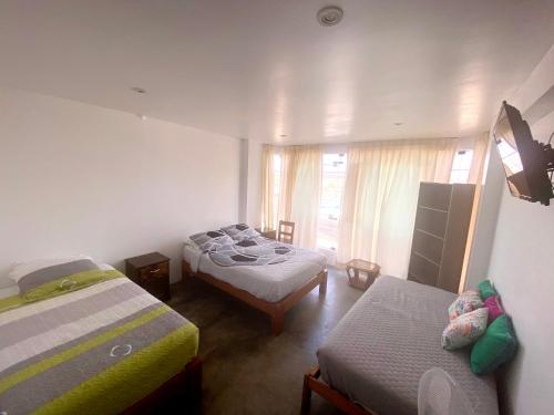 een slaapkamer met 2 bedden en een raam bij Killamoon House Paracas in Paracas