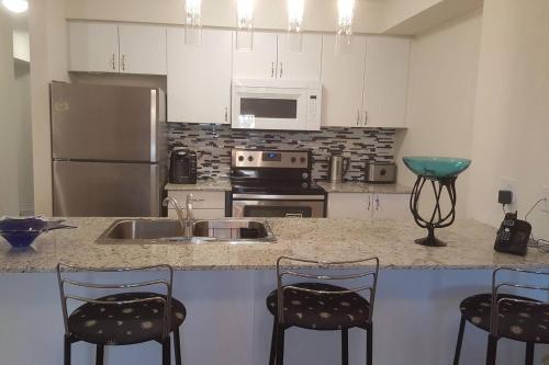 a kitchen with a counter with chairs and a sink at Specious 2 Bedroom Condo in Collingwood in Collingwood
