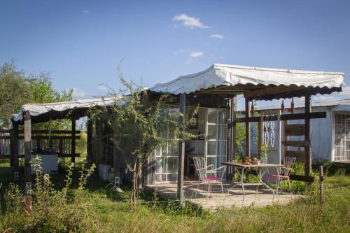 una pequeña casa con una mesa y sillas en el patio en Uy - ROMÁNTICA Cabaña en entorno Natural único en Mercedes