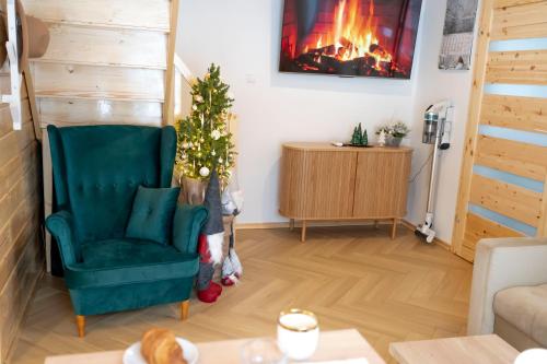 a living room with a christmas tree and a green chair at Pod Kalwarią in Nowosiółki Dydyńskie