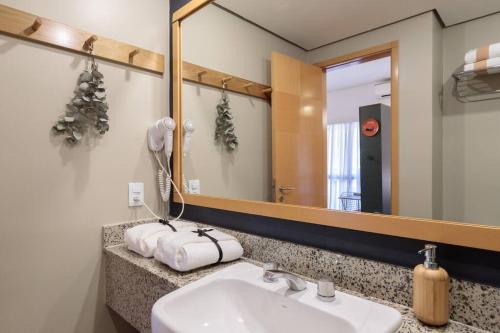 uma casa de banho com um lavatório e um espelho em L.A.R. Jardins. Limpeza diária, vaga e bikes em São Paulo