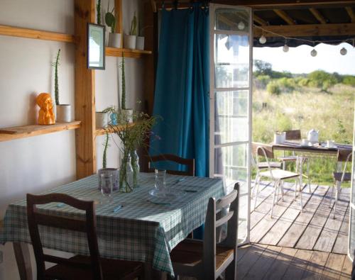 comedor con mesa y balcón en Uy MÁGICA Cabaña en entorno Natural único, en Mercedes