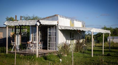 Casa blanca pequeña con mesa y sillas en Uy MÁGICA Cabaña en entorno Natural único, en Mercedes