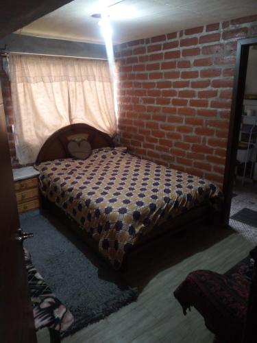a bedroom with a bed with a brick wall at Mamá Naty y sus Neguitos in Chambo