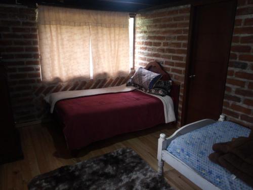 a bedroom with a red bed and a brick wall at Mamá Naty y sus Neguitos in Chambo