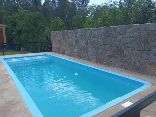 uma piscina com uma parede de pedra e uma piscina azul em Cabañas Raíces de la Estancia 2 em El Amparo