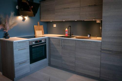 a kitchen with gray cabinets and a stove top oven at Cozy apartment with sea view in Tromsø