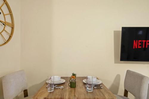 a wooden table with plates and glasses on it at LT Properties comfy Studio Apartment in Luton