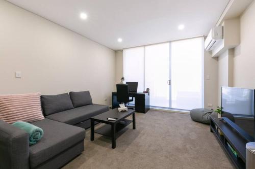 een woonkamer met een bank en een tv bij Comfortable apartment, near Parramatta CBD! in Merrylands