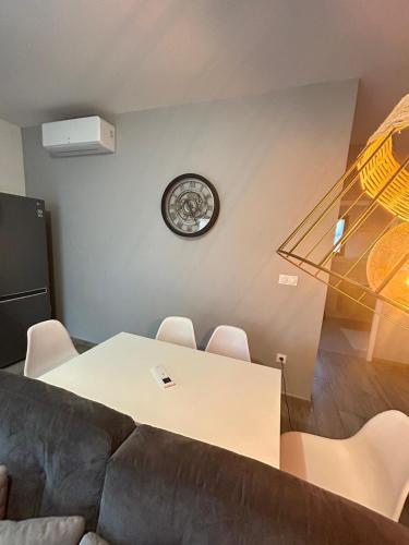 a living room with a table and a clock on the wall at Bella Vista, parking gratuit, 5 min Auxerre in Monéteau