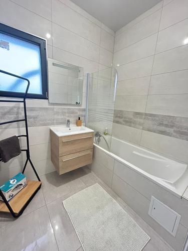 a white bathroom with a tub and a sink and a bath tubermott at Bella Vista, parking gratuit, 5 min Auxerre in Monéteau