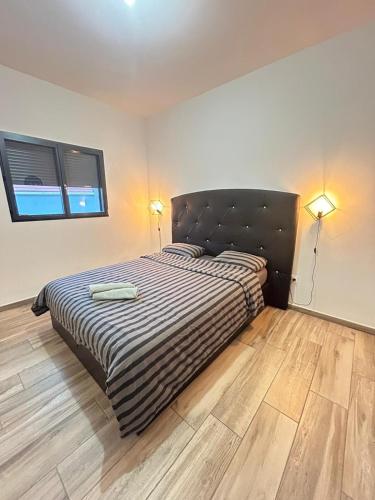 a bedroom with a bed with a black headboard and wooden floors at Bella Vista, parking gratuit, 5 min Auxerre in Monéteau
