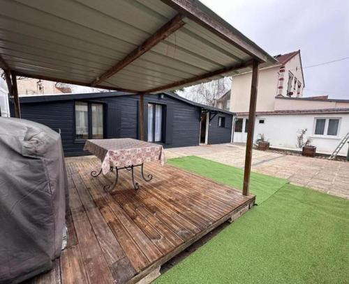 a patio with a table on a wooden deck at Maison wifi gratuit 15min de Paris in Houilles