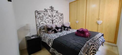 um quarto com uma cama preta e branca com almofadas roxas em 1B Barabas em Mijas Costa
