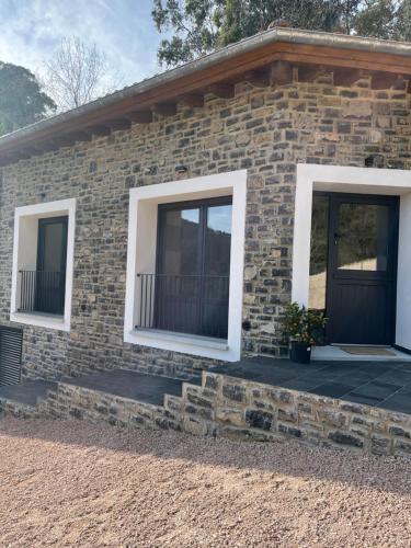 a brick house with two windows and a porch at Apartamentos Rurales El Solsuco Casa MariaCarlos in Villaviciosa