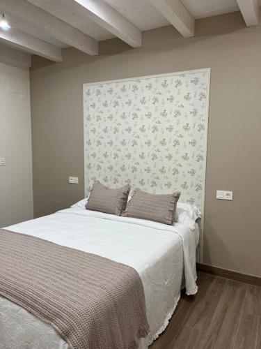a bedroom with a bed with white sheets and a wall at Apartamentos Rurales El Solsuco Casa MariaCarlos in Villaviciosa