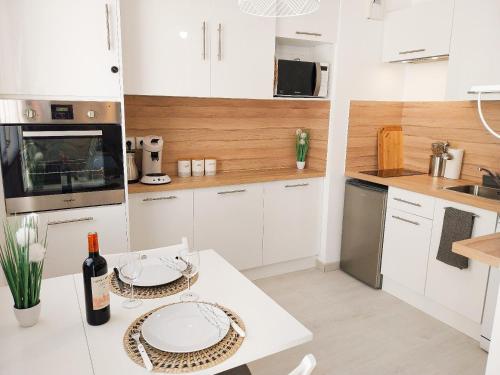 a kitchen with white cabinets and a table with plates on it at Escapade au cœur de Luce chartres in Luce