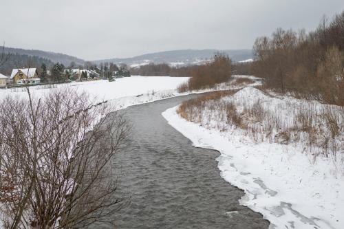 a river with snow on the sides of it at Pod Kalwarią in Nowosiółki Dydyńskie