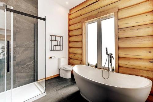 uma casa de banho com uma banheira branca e um WC. em Le Grand Phoenix - lake side & jacuzzi em Saint Come