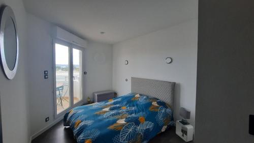 une chambre avec un lit avec une couette bleue et une fenêtre dans l'établissement 7 Quai Des Rêves 3 étoiles !, à Sète