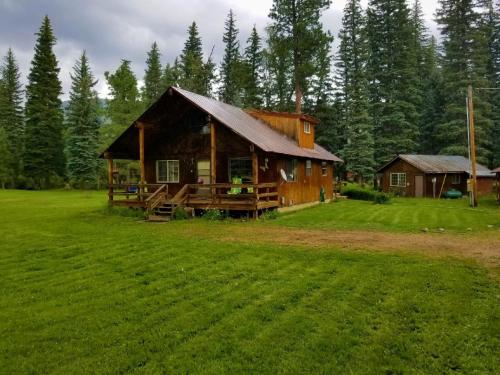 a log cabin in the middle of a grass field at Bear Paw Lodge in Vallecito