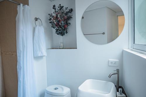 a bathroom with a sink and a mirror and a toilet at HELICONIA Enjoy new comfortable studio apartment with terrace in Cali