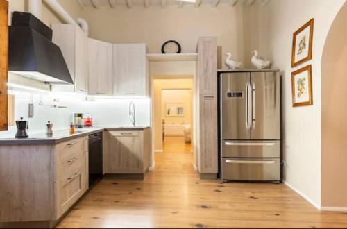 a kitchen with a stainless steel refrigerator and wooden floors at Maestra Exclusive Chianti House, Tuscany in Poggibonsi