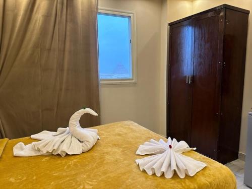 Dos cisnes hechos de toallas en una cama en Happy pyramids view en Kafret el-Gabal