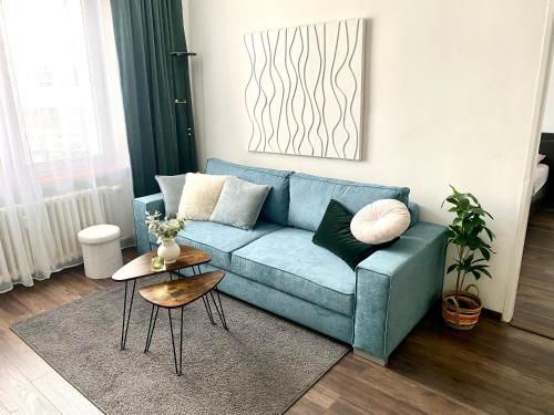 a living room with a blue couch and a table at James Dean apartment - next to Nivy Bus station & Mall (Free parking on the weekend) in Bratislava