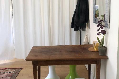 a wooden table with two green legs next to a curtain at Appartement calme et lumineux 4 voyageurs in Malakoff