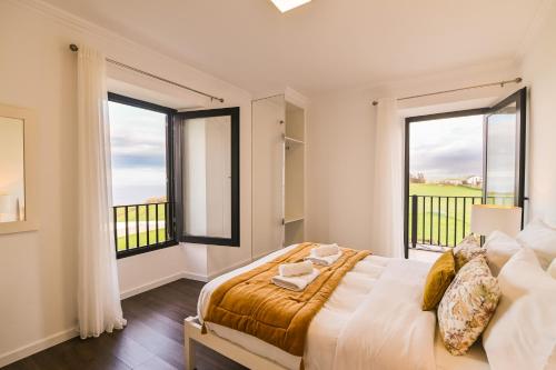a bedroom with a large bed and two large windows at Casa da Belavista with Jacuzzi in Nordeste