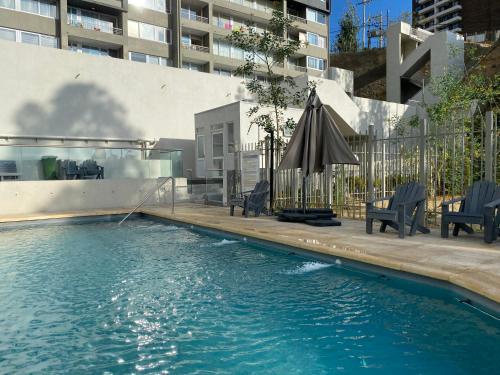 an outdoor swimming pool with an umbrella and chairs at Departamento en Viña del Mar in Viña del Mar