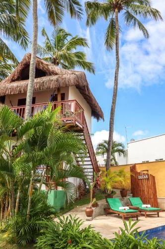 a resort with a thatched roof and palm trees at Pousada Aconchego da Pipa in Pipa