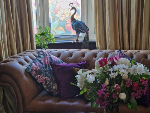 a brown leather couch with a bouquet of flowers at Flawsome Stays Unique Home w Quirky basement for 12 Guests by Harbour and Town in Ramsgate