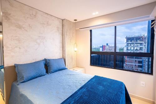 a bedroom with a blue bed and a large window at Park Del Prado #602 - Intermares por Carpediem in João Pessoa